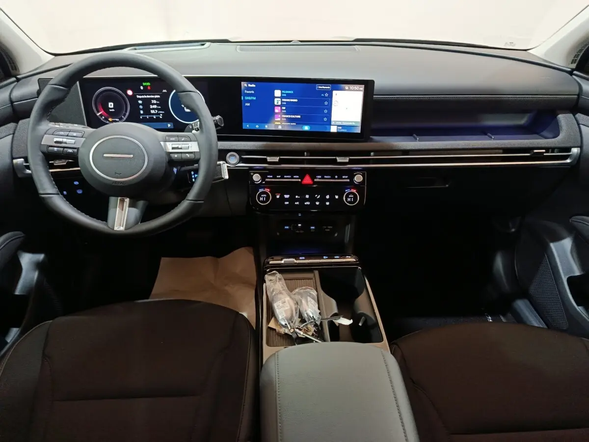 Vue intérieure avant du tableau de bord noir du Hyundai Tucson 2025 avec écran tactile large et volant multifonctions.