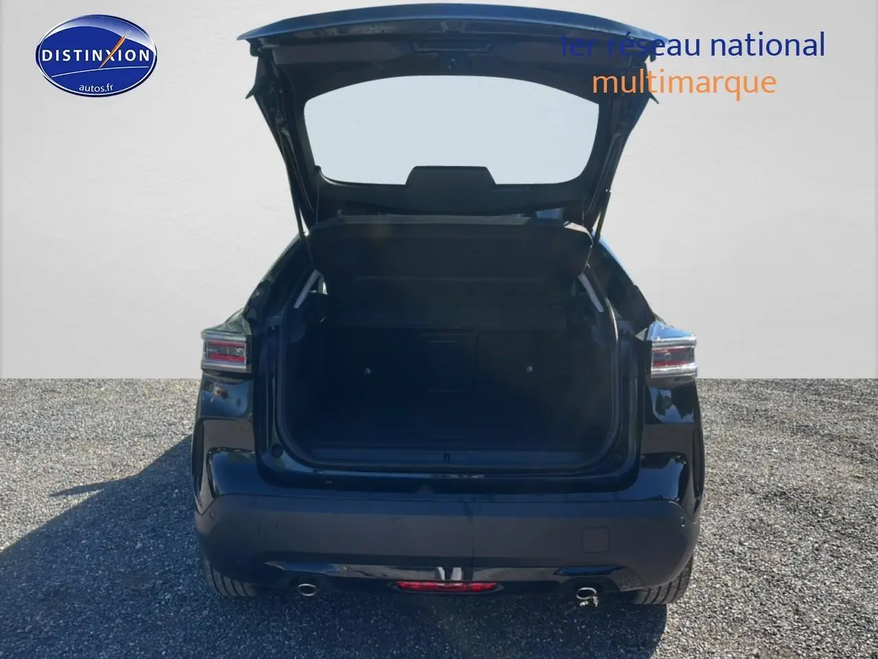 Vue arrière d'une Citroën C4 noire 2025 avec coffre ouvert sur un sol gravillonné.