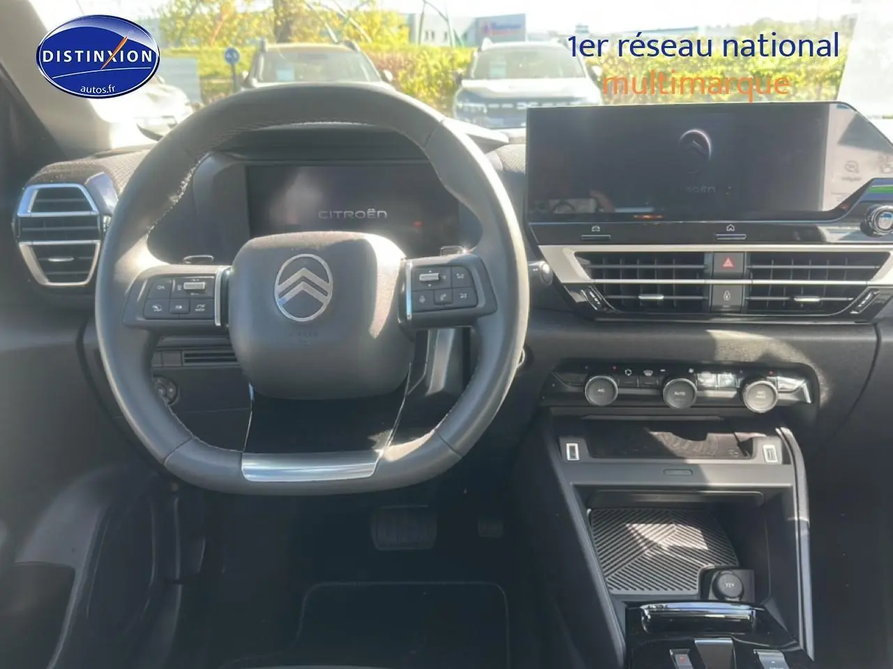 Vue intérieure avant du tableau de bord et volant cuir noir de la Citroën C4 hybride 2025 avec écran tactile et commandes au volant.