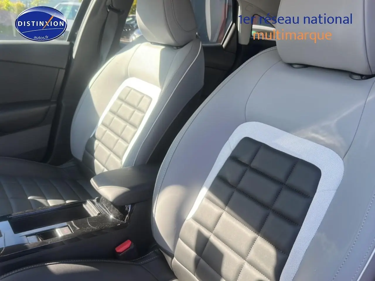 Vue rapprochée des sièges avant bi-ton gris clair et noir avec accoudoir central d'une Citroën C4 hybride 2025.