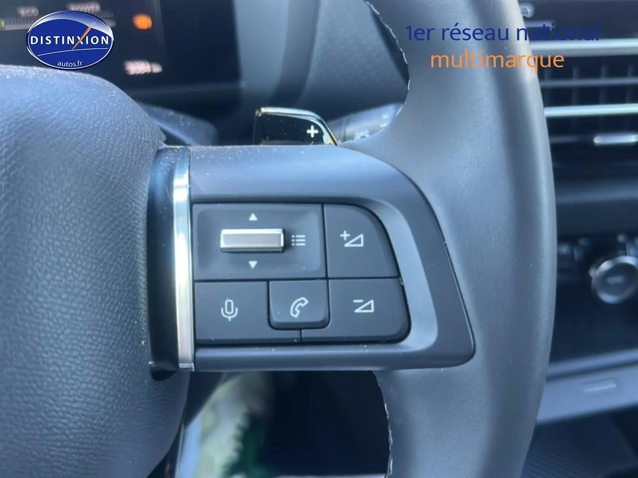 Gros plan sur les commandes au volant cuir noir de la Citroën C4 hybride 2025, avec boutons de volume et appel.