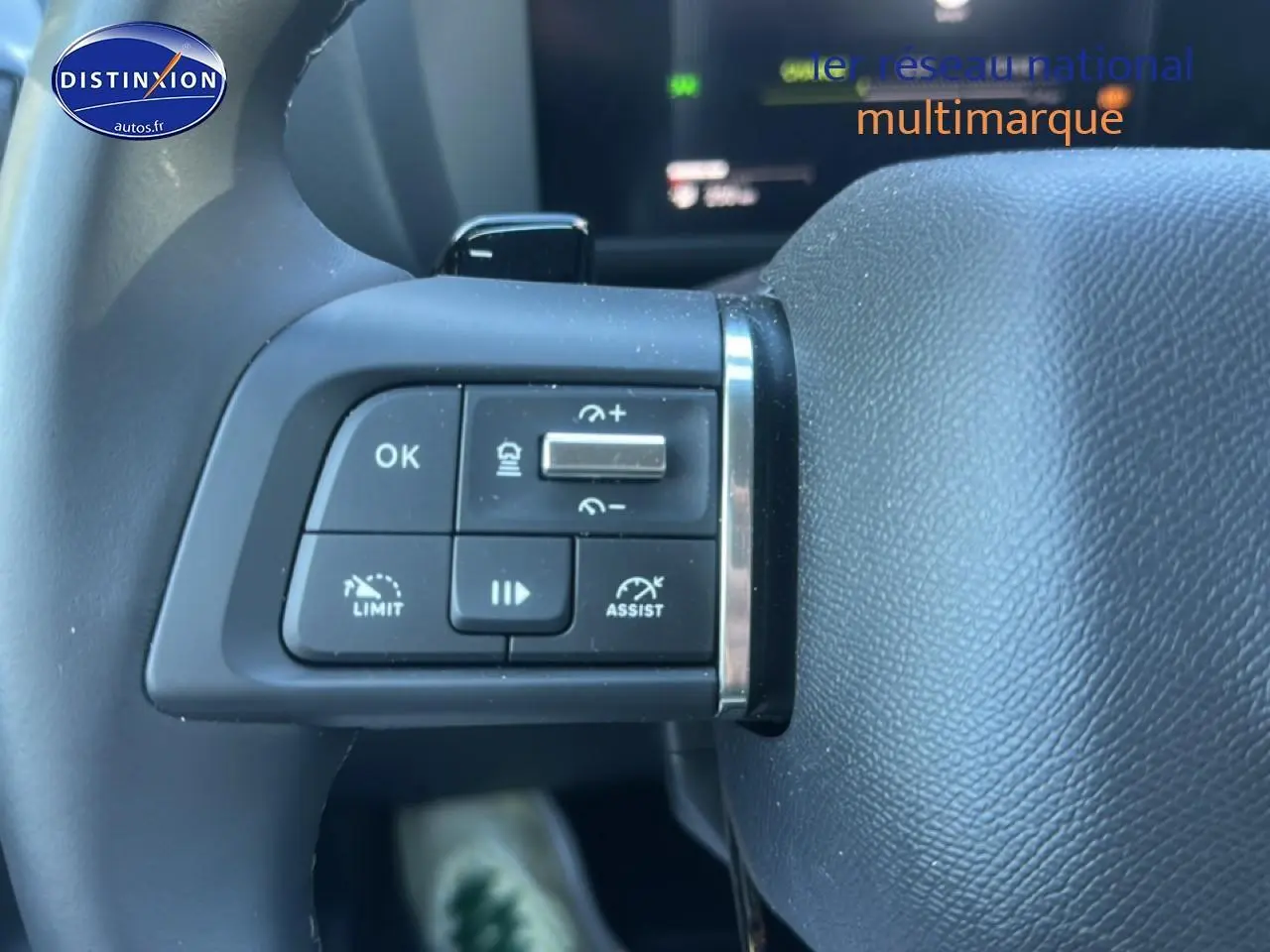 Gros plan sur les commandes au volant côté gauche d'une Citroën C4 noire hybride 2025, avec boutons de régulateur et assistant.