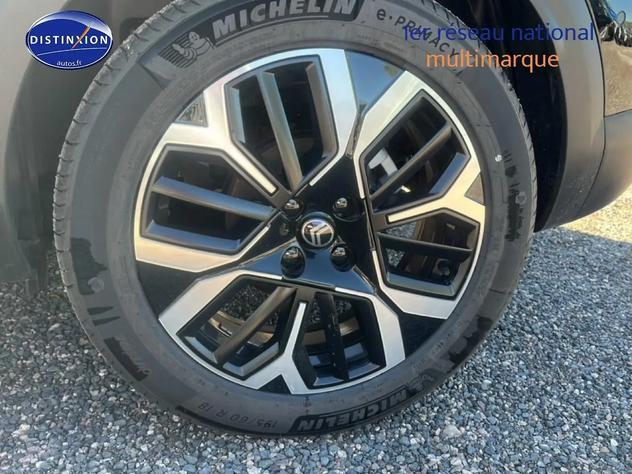 Gros plan sur la jante alu noire et argentée d'une Citroën C4 noire, vue côté droit.