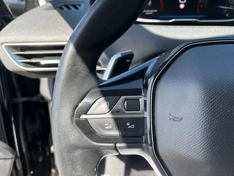 Gros plan sur les commandes gauche du volant noir du Peugeot 3008 2021 HDI 130 cv Allure Pack EAT8, avec tableau de bord en arrière-plan.