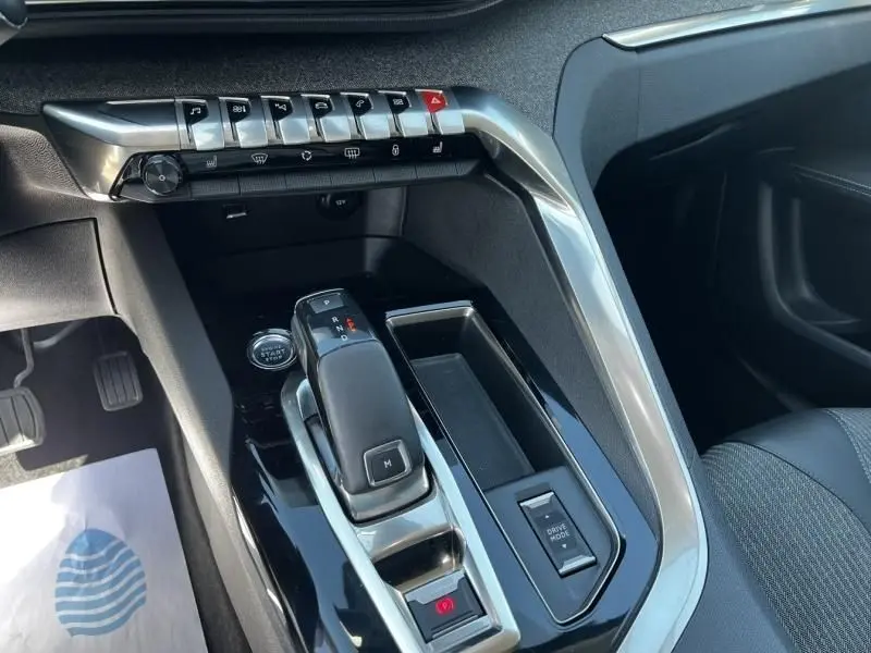 Gros plan sur la console centrale noire du Peugeot 3008 2021, avec levier de boîte auto et boutons de commande argentés.
