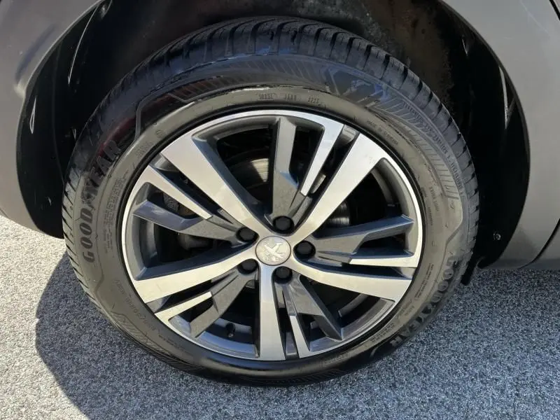 Gros plan sur la roue avant gauche d’un Peugeot 3008 noir 2021, avec jante alliage bicolore et pneu Goodyear.