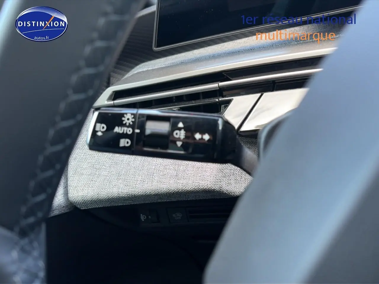 Détail du commodo d'éclairage à gauche du volant dans l'habitacle du Peugeot 3008 bleu 2025.