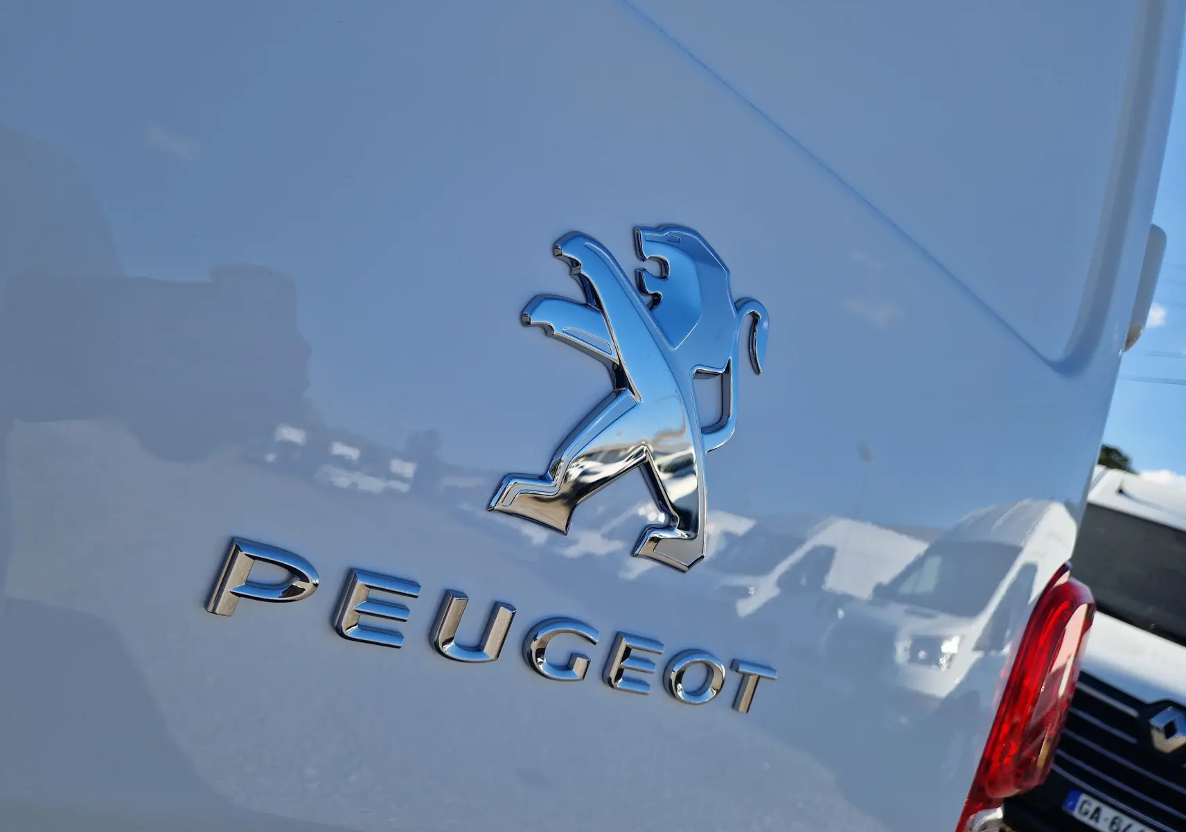Gros plan sur l'arrière blanc d'un Peugeot Expert Fourgon avec le logo lion chromé et le nom PEUGEOT visible.