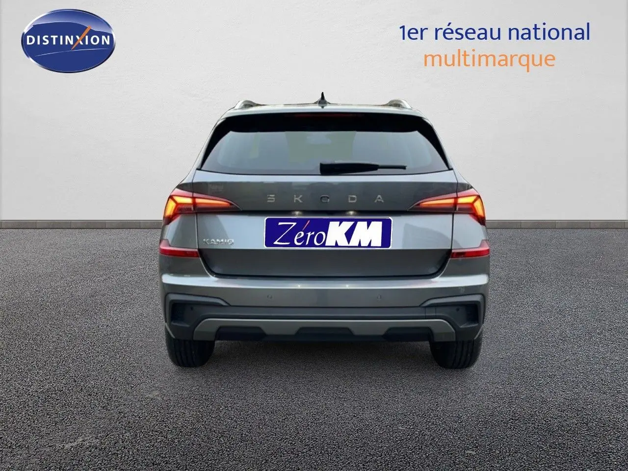 Vue arrière d'un Skoda Kamiq gris graphite métal 2025 avec feux LED allumés sur fond neutre.