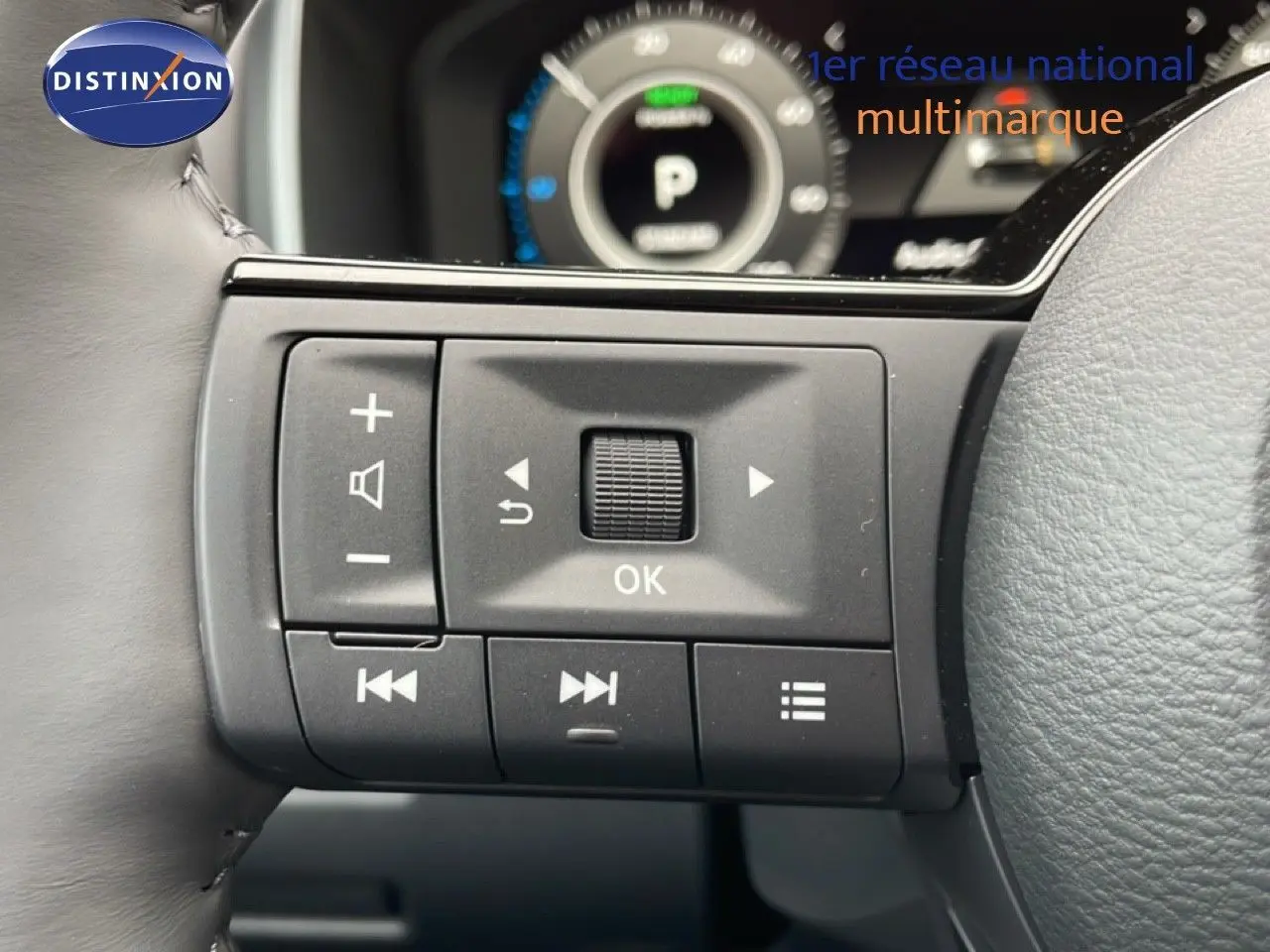 Gros plan sur les commandes gauche du volant du Nissan Qashqai gris, avec tableau de bord numérique en arrière-plan.