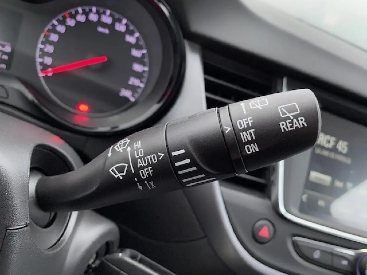 Gros plan sur la commande des essuie-glaces à gauche du volant dans l’habitacle d’un Opel Crossland gris métallisé 2022.