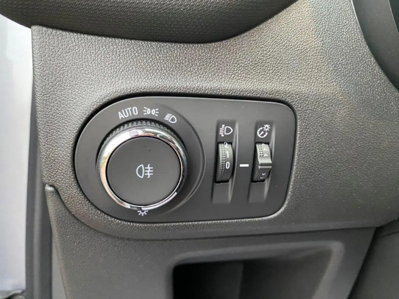 Gros plan sur les commandes d’éclairage du tableau de bord de l’Opel Crossland gris métallisé, côté gauche du conducteur.