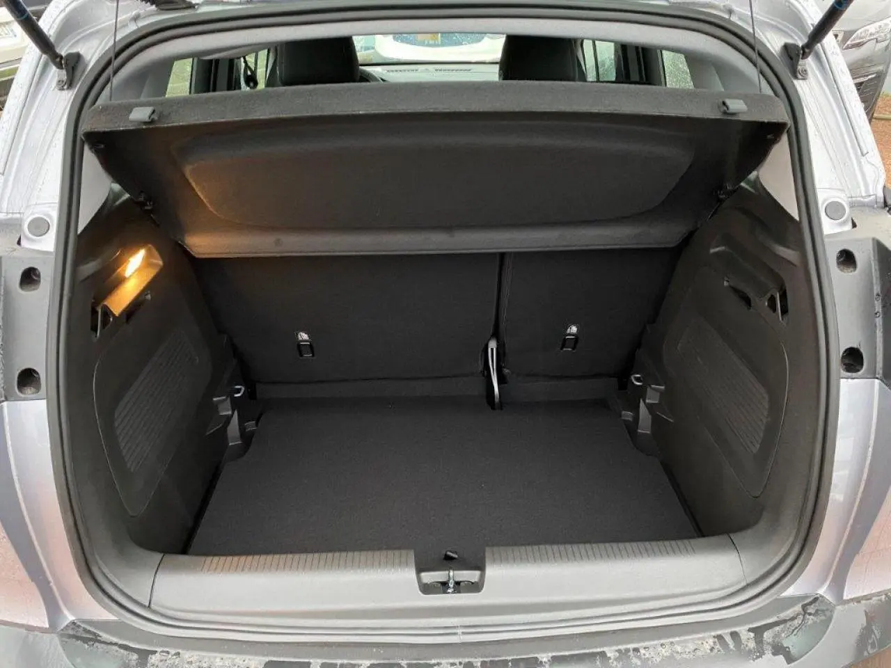 Coffre ouvert d’un Opel Crossland gris métallisé 2022, vue arrière montrant l’espace de chargement vide et l’éclairage intérieur.