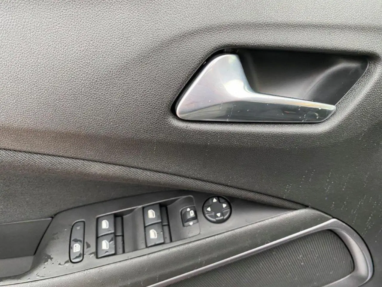 Gros plan sur la poignée intérieure et les commandes des vitres côté conducteur d'un Opel Crossland gris métallisé.