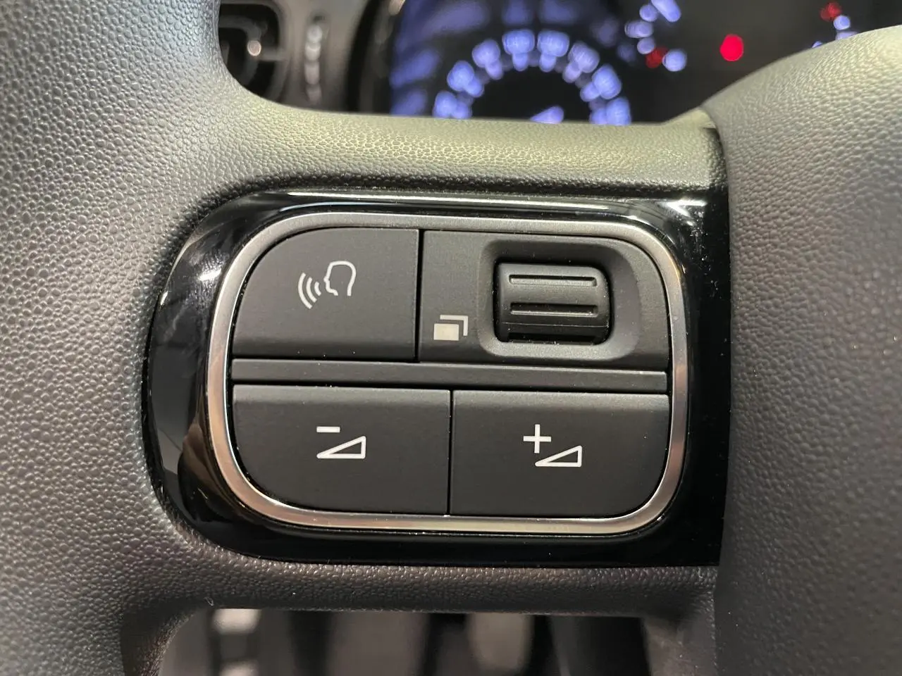 Gros plan sur les commandes audio au volant de la Citroën C3 2024, finition noir brillant avec surpiqûres jaunes.