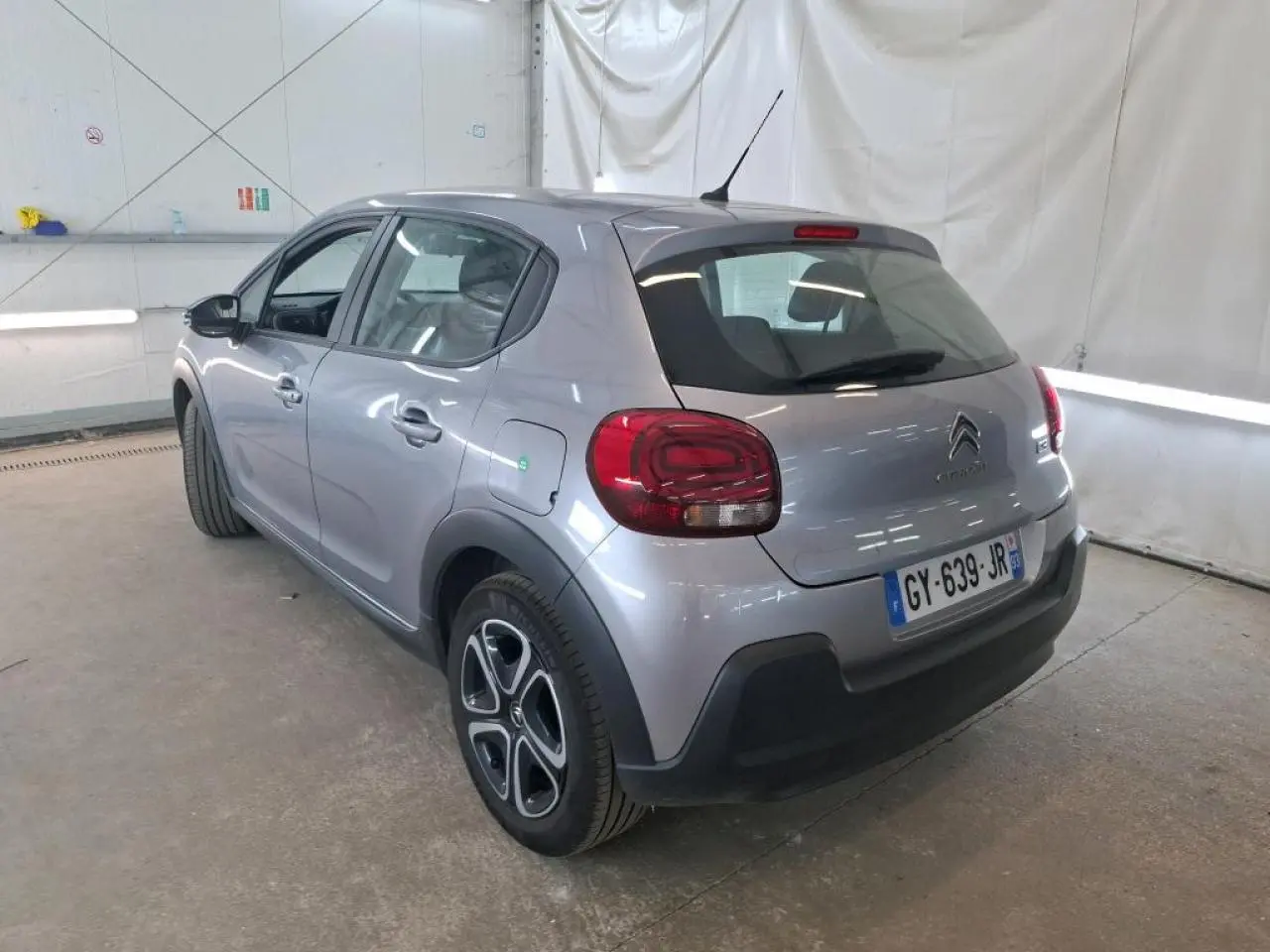 Vue 3/4 arrière droite d'une Citroën C3 gris foncé 2024 avec feux arrière arrondis et jantes spécifiques.