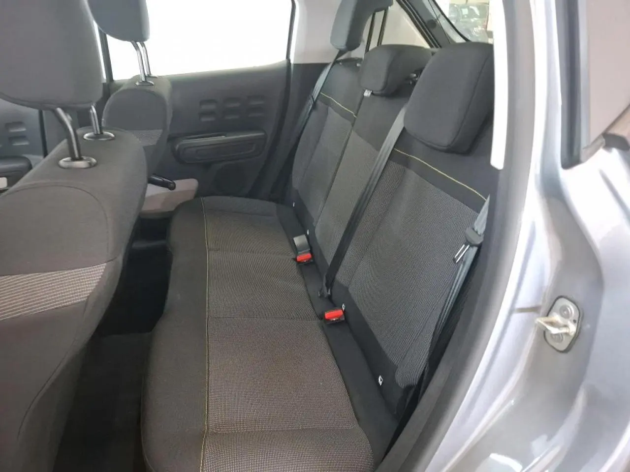 Vue intérieure côté droit sur la banquette arrière grise foncée de la Citroën C3 2024 avec surpiqûres jaunes visibles.