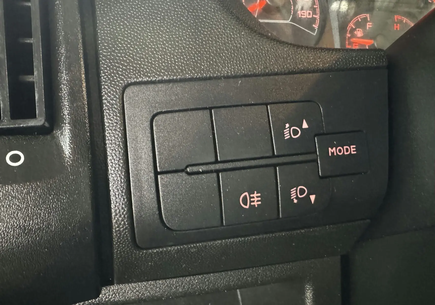 Gros plan sur les commandes d'éclairage du tableau de bord du Citroën Jumper benne rouge, version 2019.