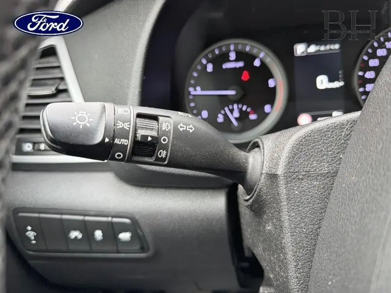 Gros plan sur la manette de commandes des phares et clignotants dans l'habitacle d'un Hyundai Tucson Phantom Black, tableau de bord en arrière-plan.