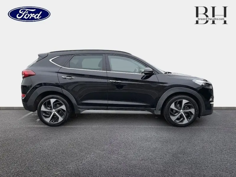 Vue latérale droite d'un Hyundai Tucson Phantom Black 2018 avec jantes alliage et barres de toit chromées.