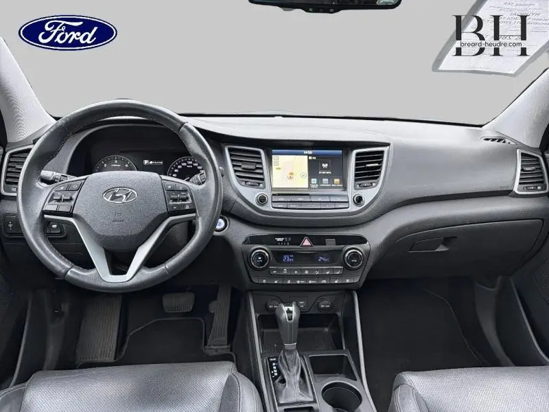 Vue intérieure avant du Hyundai Tucson 2018, tableau de bord noir avec écran tactile et volant multifonction cuir.