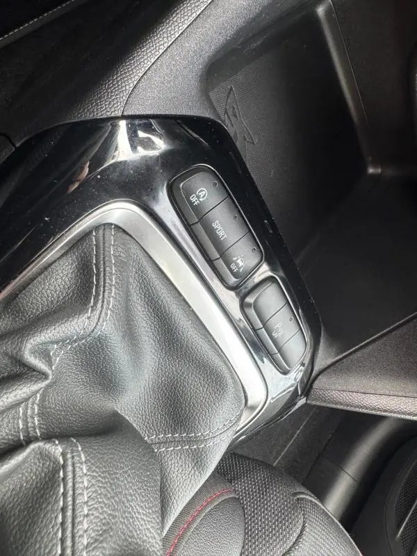 Gros plan sur la console centrale de l’Opel Corsa gris clair 2022, montrant le soufflet de levier de vitesses et les boutons de mode conduite.