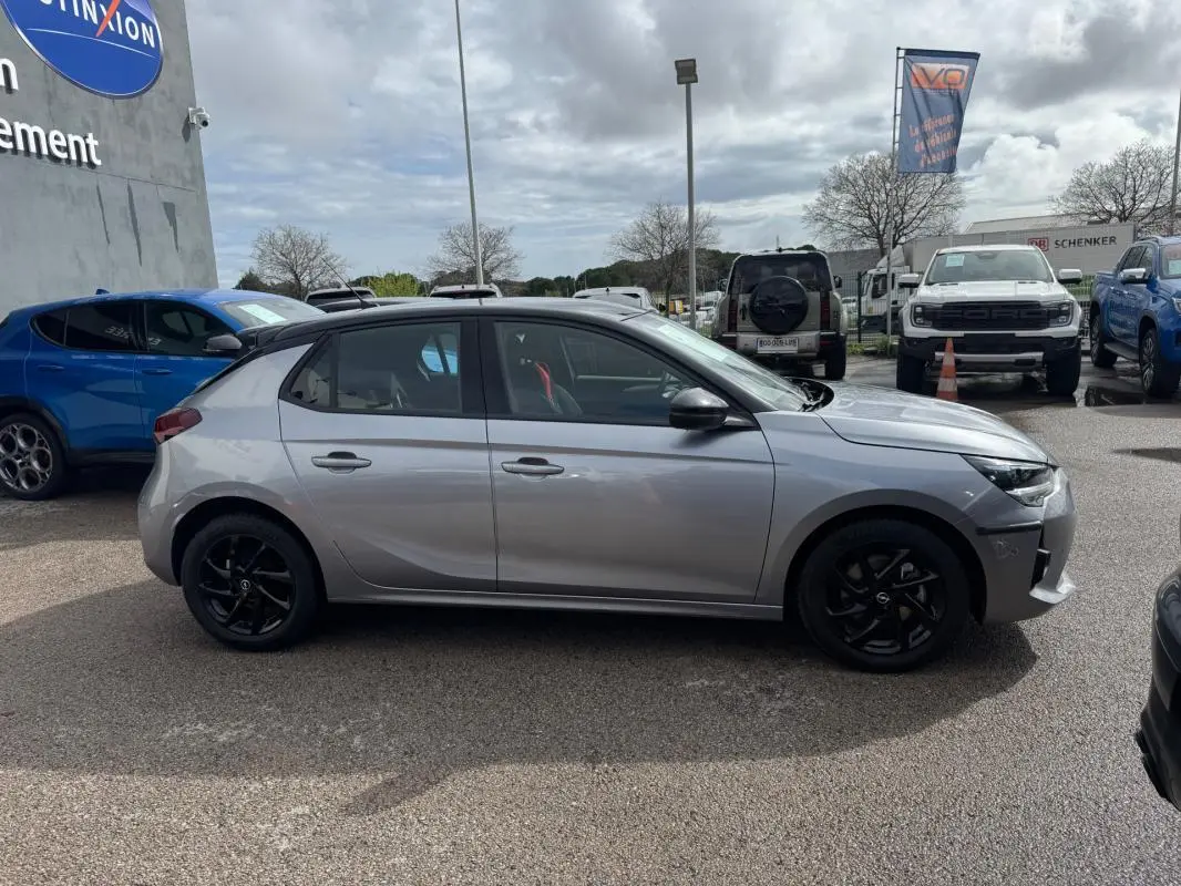 Opel Corsa gris clair vue de profil côté gauche, jantes noires et ligne GS Line visible, stationnée en extérieur.