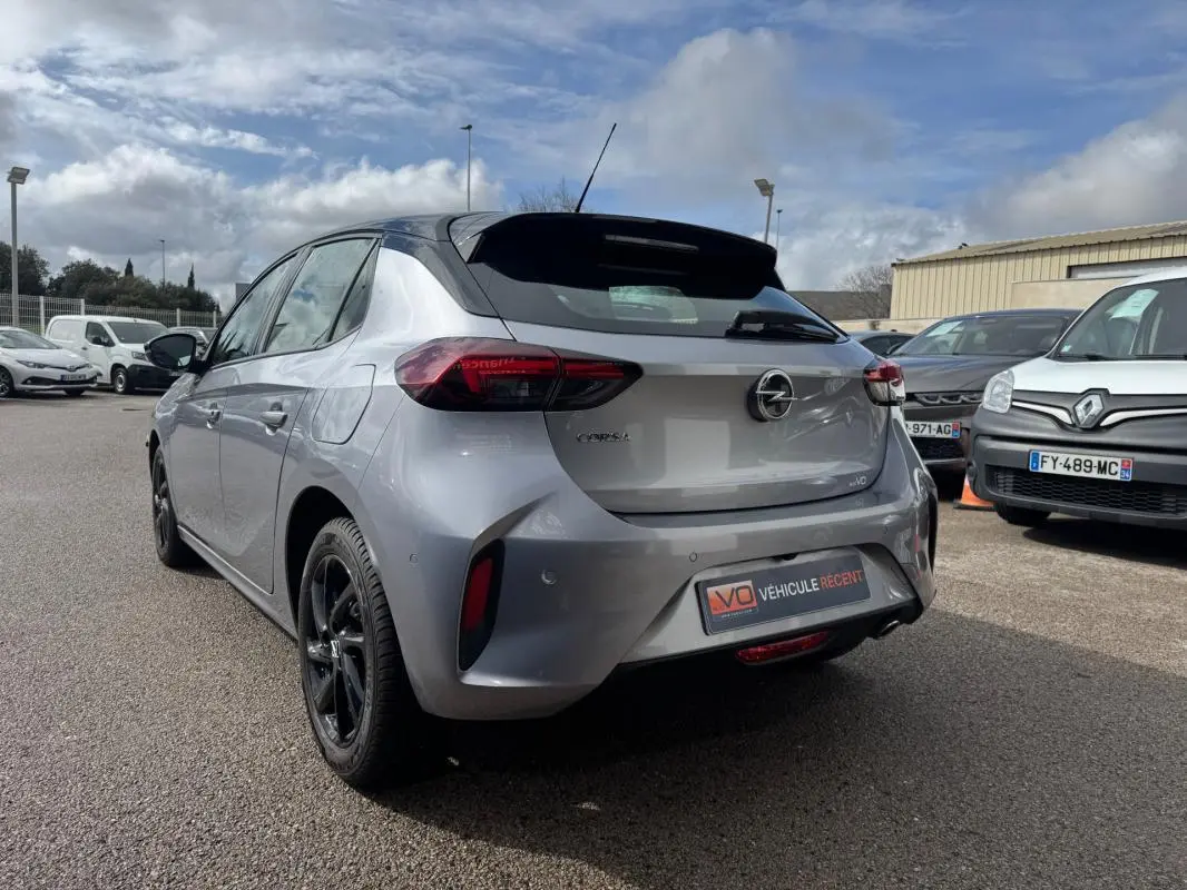 Vue 3/4 arrière droite d'une Opel Corsa gris clair 2022 avec jantes noires et badge GS Line visible au parking.