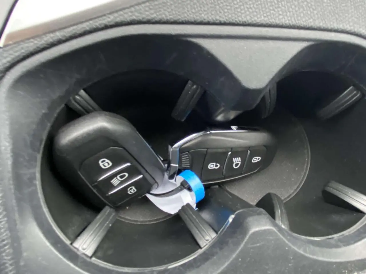 Gros plan sur les clés de la Peugeot 3008 posées dans un porte-gobelets noir à l'intérieur du véhicule.