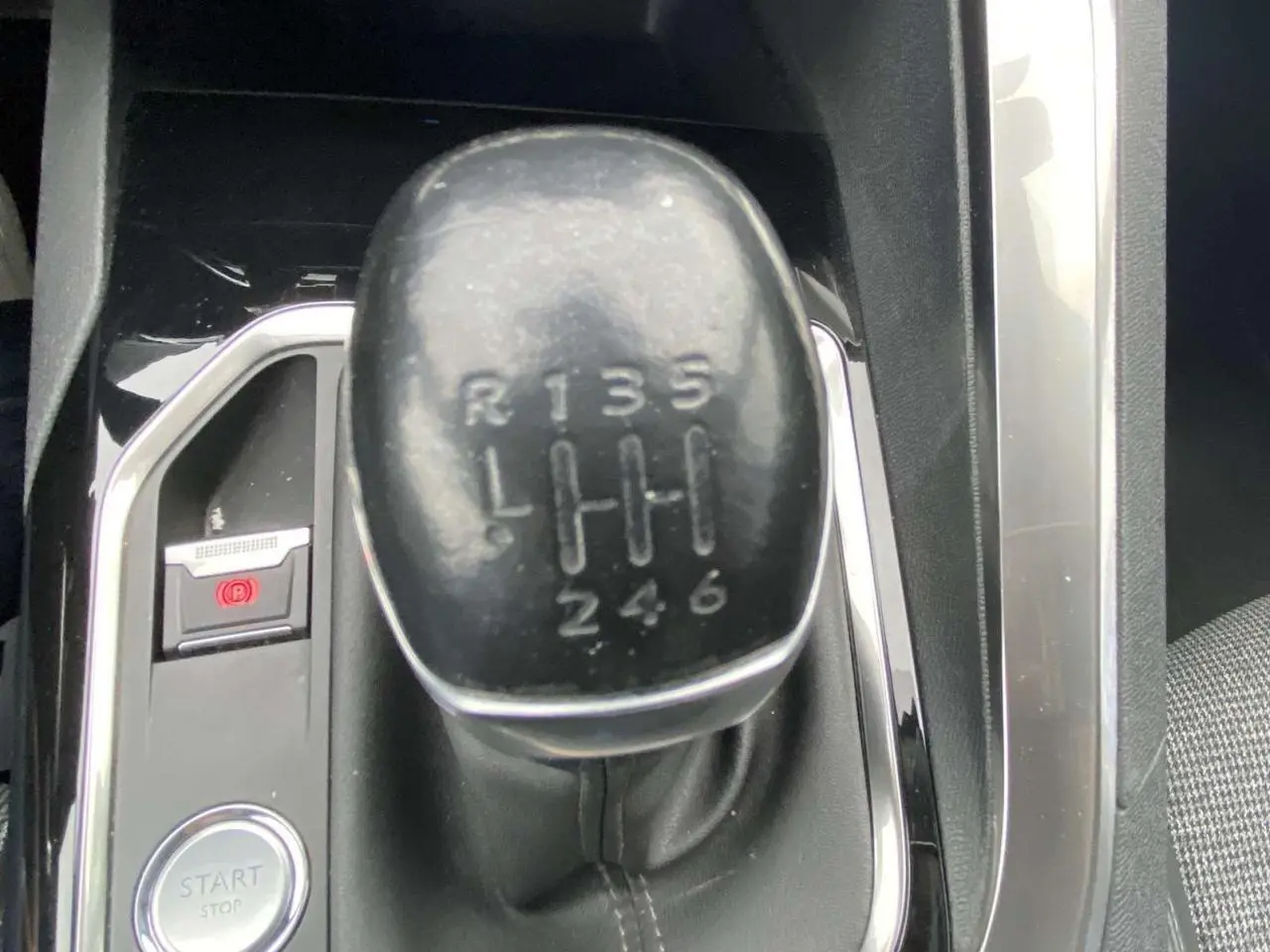 Gros plan sur le levier de vitesse manuel noir de la Peugeot 3008 blanc nacré, entouré de finitions chromées et tissu gris.