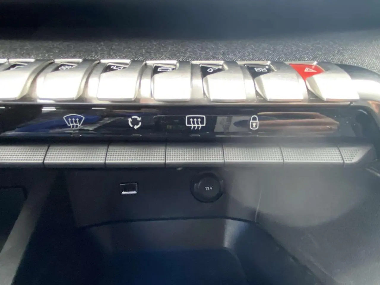 Gros plan sur les commandes centrales et prise 12V du tableau de bord du Peugeot 3008 blanc de 2017.