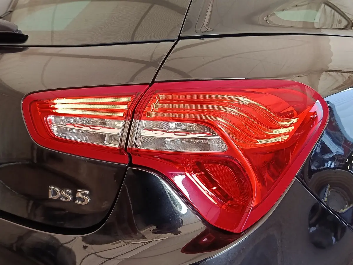 Gros plan sur le feu arrière droit rouge et le logo DS5 d’une DS5 noire brillante, vue arrière côté droit.