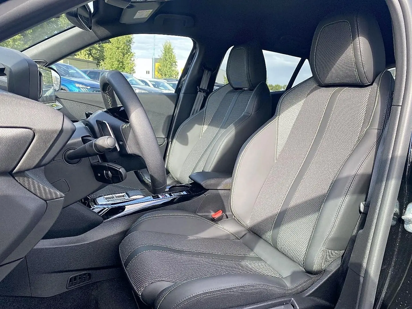 Vue intérieure côté conducteur du Peugeot 2008 1.2 hybrid 145 GT noir, sièges en tissu et cuir avec volant multifonction.