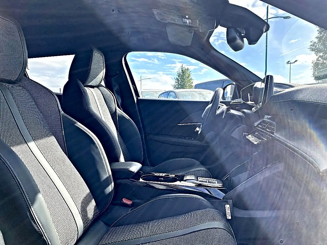 Intérieur avant du Peugeot 2008 1.2 hybrid 145 GT noir, sièges sport et tableau de bord moderne côté conducteur.