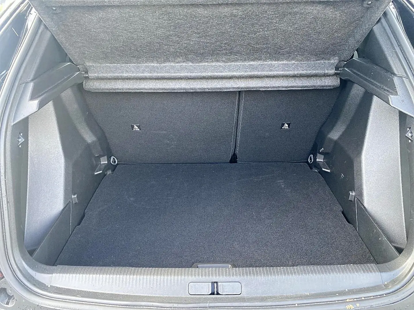 Coffre ouvert de Peugeot 2008 noir, vue arrière montrant l'espace de chargement et la banquette rabattable.