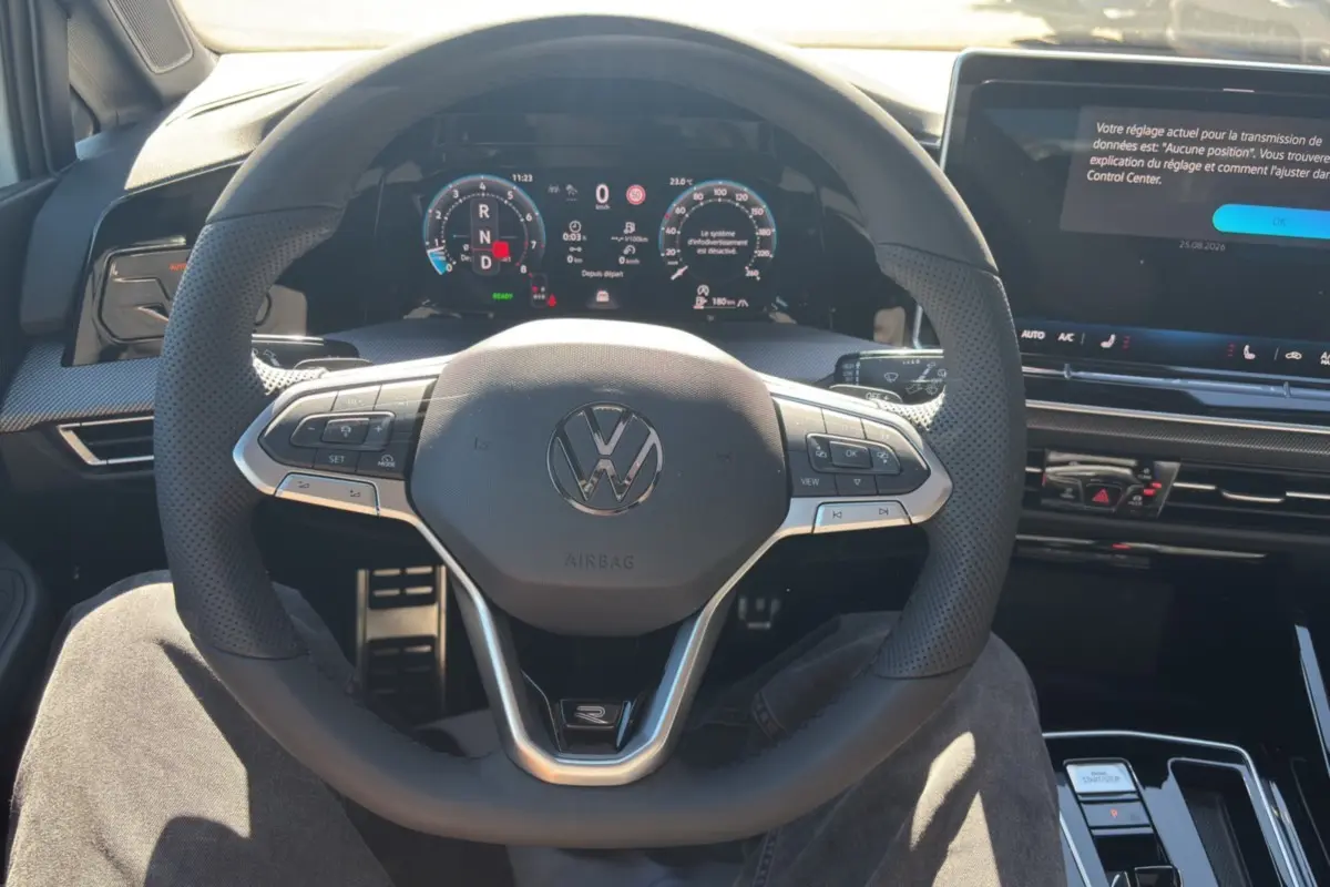 Vue intérieure centrée sur le volant cuir multifonctions et le tableau de bord numérique d'une Volkswagen Golf TDI 150 R-Line.