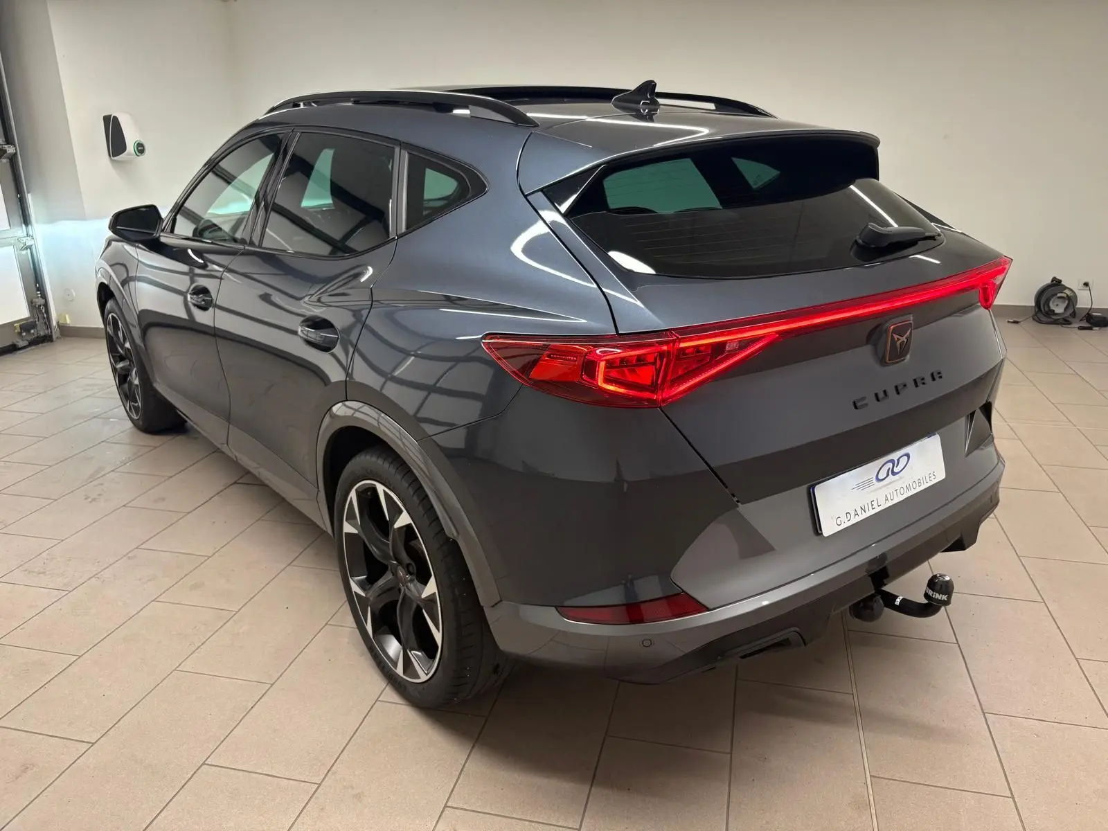 Vue 3/4 arrière droite d'un CUPRA Formentor gris magnétique 2023 avec feux arrière LED et attelage visible