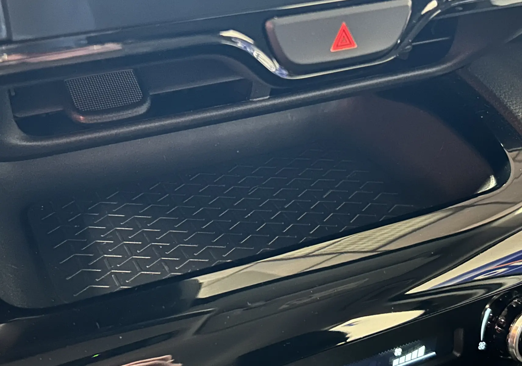 Détail de la console centrale noire avec rangement et bouton de signalisation d'urgence rouge sur Toyota Yaris Cross 2025.