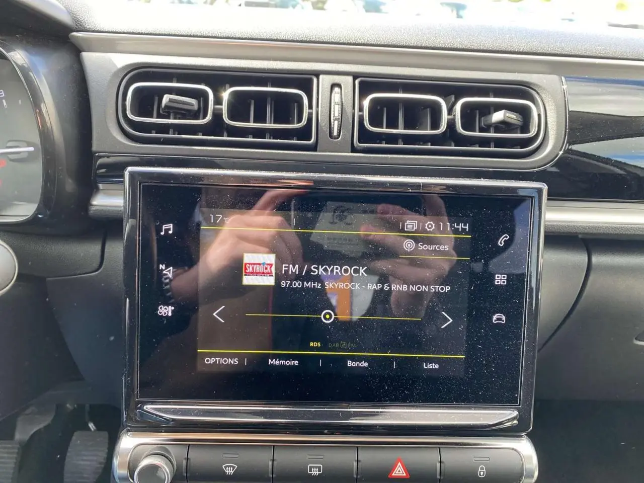 Vue rapprochée de la tablette tactile centrale de la Citroën C3 2021, affichant la radio FM Skyrock, entourée d'aérateurs noirs.
