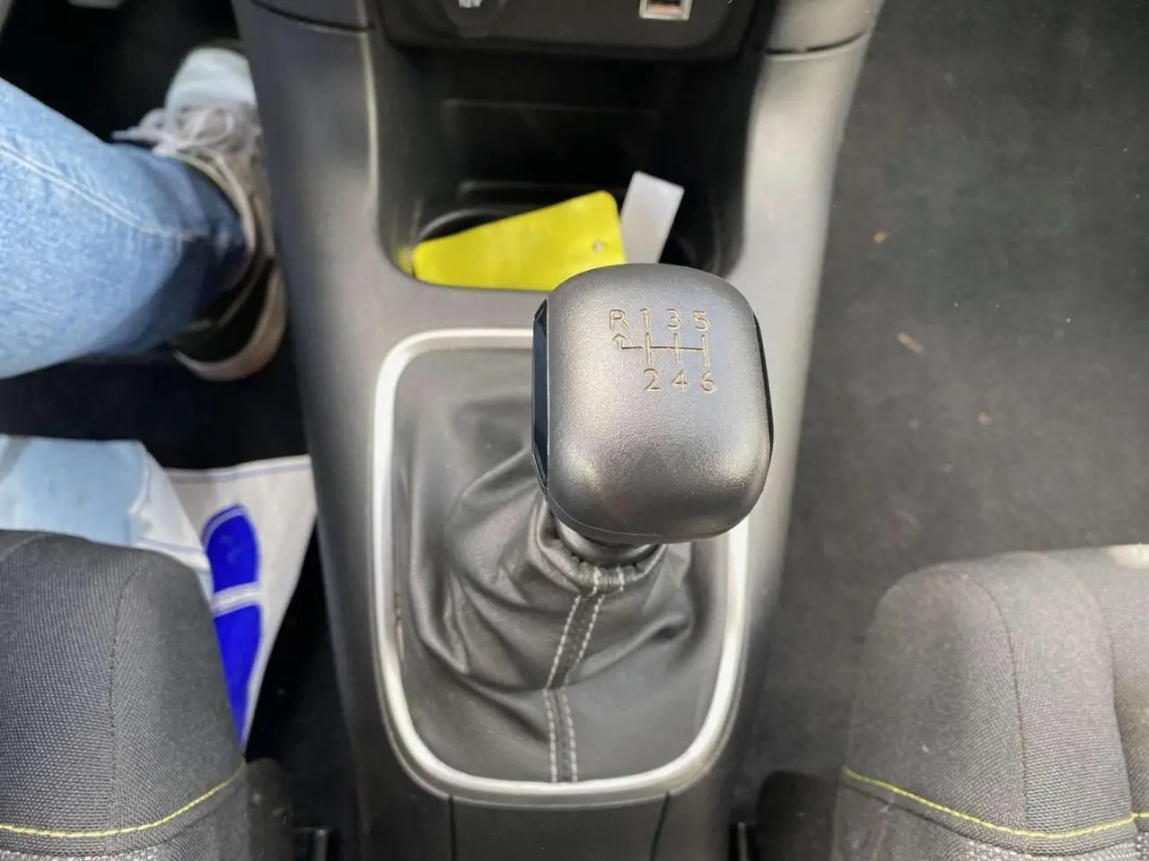 Gros plan sur le levier de vitesses manuel noir de la Citroën C3 2021, intérieur avec sièges gris et couture jaune.