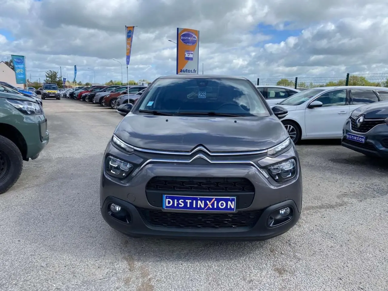 Vue avant d'une Citroën C3 gris platinium avec calandre et phares distinctifs sur un parking extérieur.