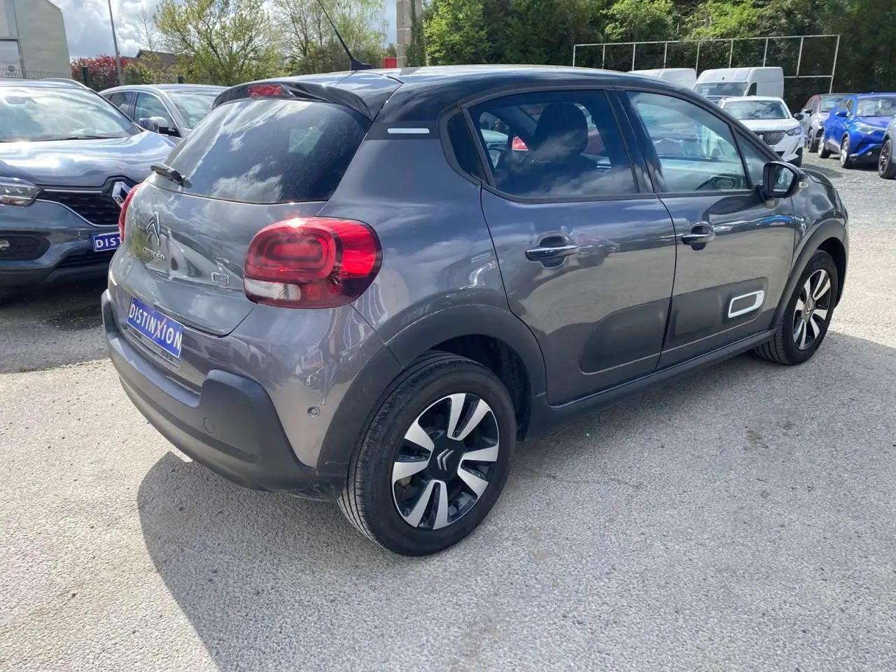 Vue 3/4 arrière droite d'une Citroën C3 gris platinium avec toit noir et jantes alliage distinctives.