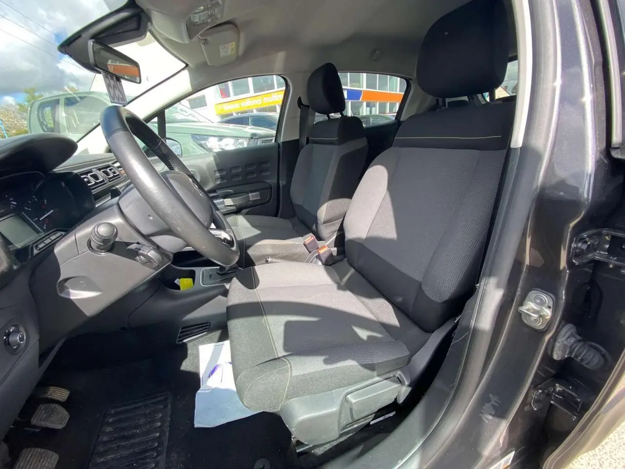 Vue intérieure côté conducteur de la Citroën C3 gris platinium, montrant les sièges avant et le volant.