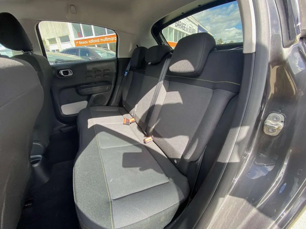 Vue intérieure côté arrière droit de la Citroën C3 gris platinium, montrant la banquette arrière et la portière ouverte.