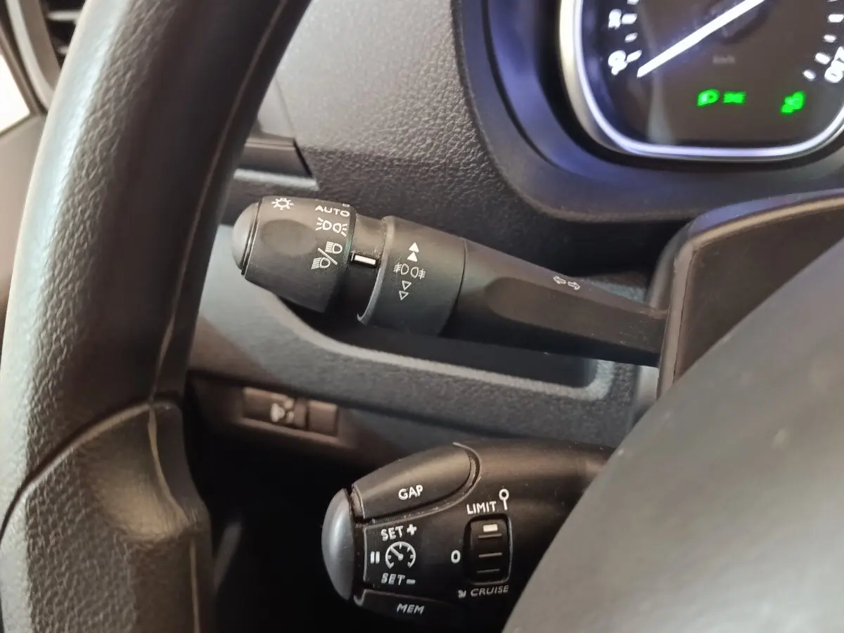 Gros plan sur le volant noir du Peugeot Expert Fourgon, montrant les commandes de régulateur et des phares.