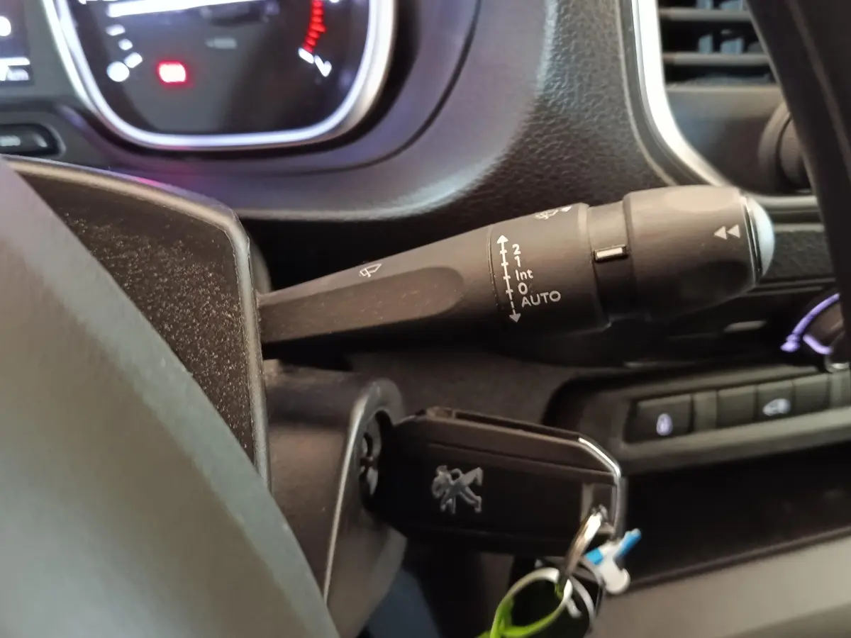 Gros plan sur la clé insérée et le commodo d’essuie-glace côté gauche du tableau de bord du Peugeot Expert Fourgon blanc.