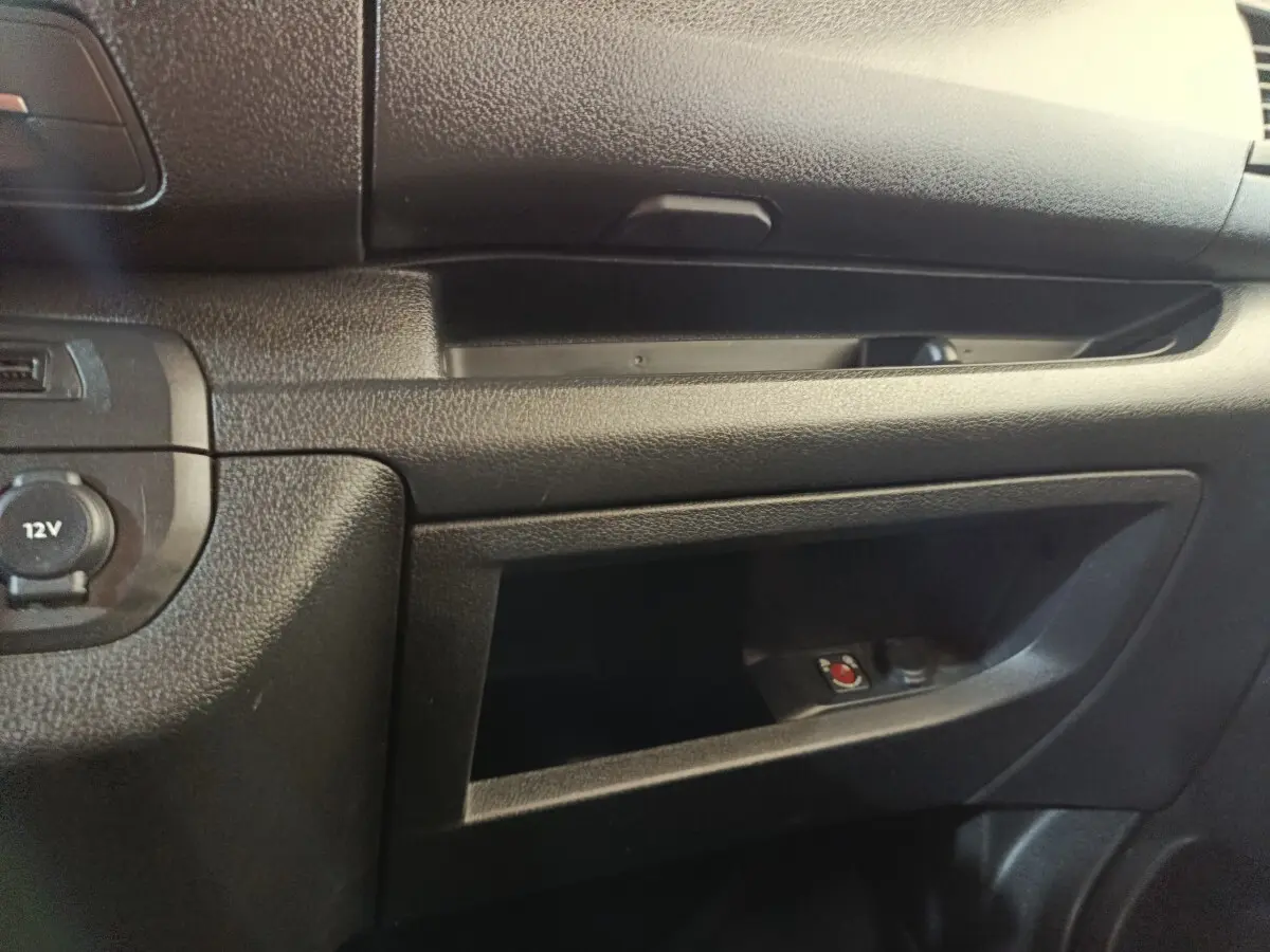 Détail de la console centrale noire côté passager du Peugeot Expert Fourgon blanc, avec prise 12V visible.