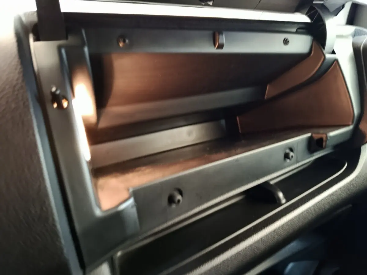 Gros plan sur la boîte à gants ouverte du Peugeot Expert Fourgon blanc, intérieur noir avec éclairage intérieur visible.