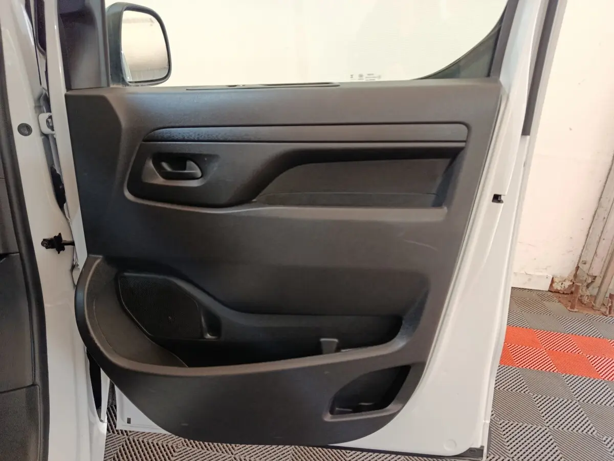 Vue intérieure de la porte côté gauche du Peugeot Expert Fourgon blanc, avec panneau de porte noir et poignée intégrée.