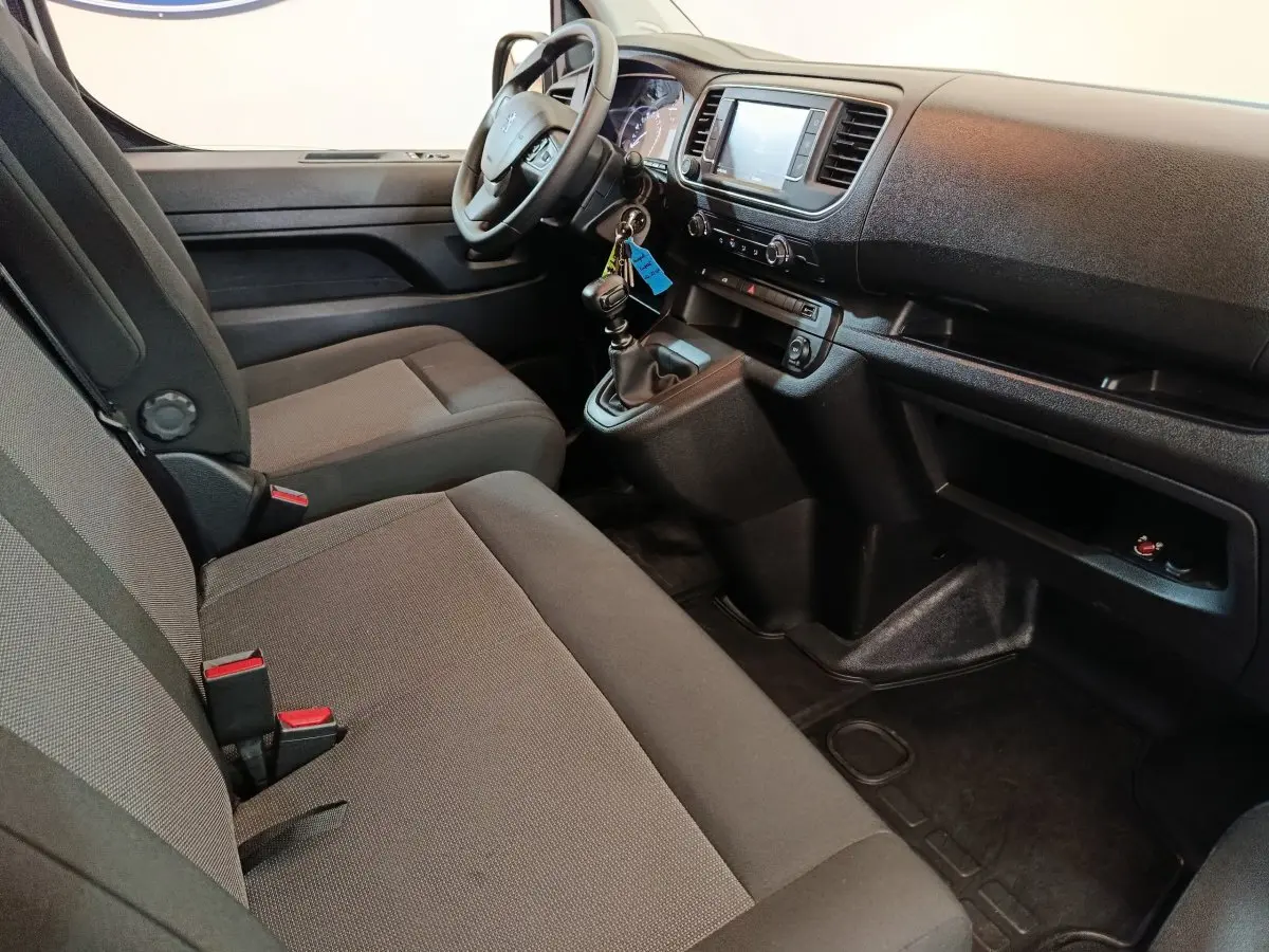 Vue intérieure côté conducteur du Peugeot Expert Fourgon blanc 2023, montrant le tableau de bord et les sièges avant gris.
